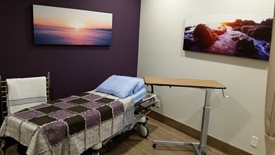 Clini exam room with stretcher and bedside table